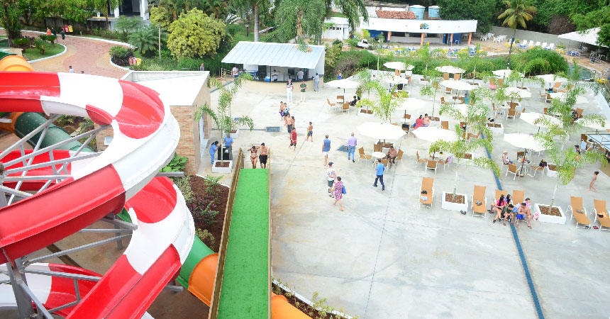 Vista do alto do toboágua vermelho e branco, com a escada de acesso e o deck com guarda-sóis do Metropolitan Park