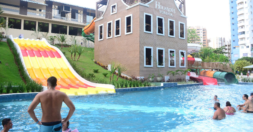 Rampa de descida amarela e vermelha ao lado do prédio Holandês Voador, com banhistas na piscina do Metropolitan Park
